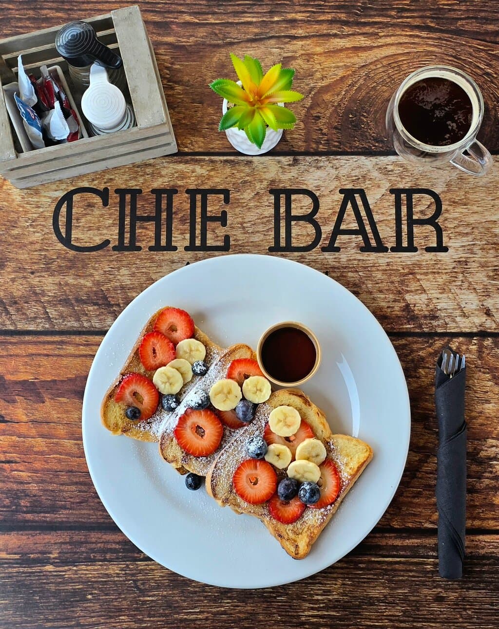 French Toast with fresh strawberries, blueberries and banana. Sprinkled with powdered sugar and served with syrup on the side.